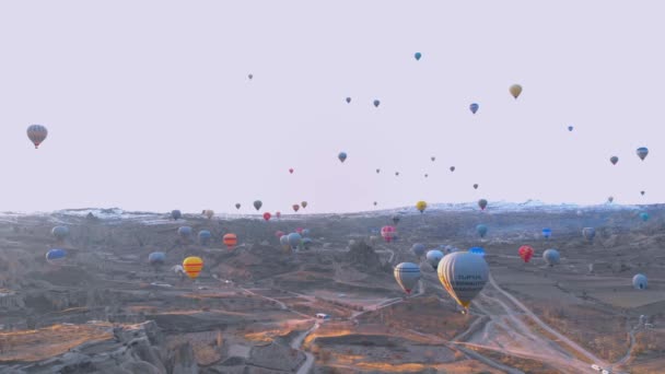 Paisaje del valle aéreo con muchos globos de aire caliente en el cielo azul claro al amanecer en Capadocia, Turquía — Vídeo de stock