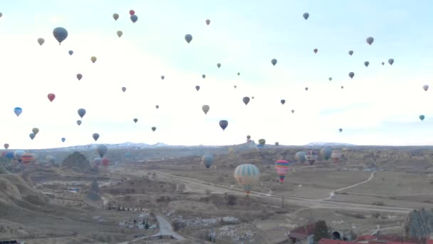 Paisaje del valle aéreo con muchos globos de aire caliente en el cielo azul claro al amanecer en Capadocia, Turquía — Vídeos de Stock