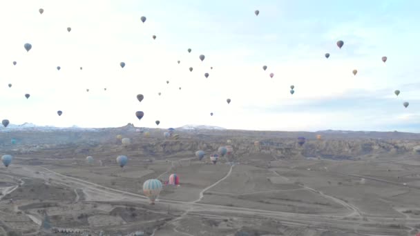 Paisaje del valle aéreo con muchos globos de aire caliente en el cielo azul claro al amanecer en Capadocia, Turquía — Vídeo de stock