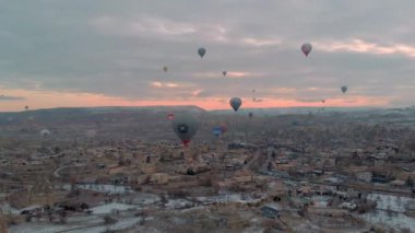 Türkiye 'nin başkenti Kapadokya' da kış mevsiminde güneş doğarken kızıl vadinin karlı manzarası üzerinde renkli Sıcak Hava Balonları