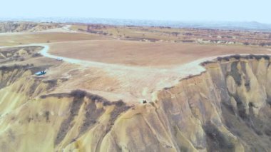 Uçurumun kenarında oturan ve Cappadocia 'daki Aşıklar Tepesi' ndeki Peri Bacaları 'nı izleyen sevimli, volkanik vadi manzarası.