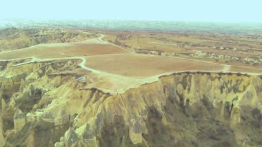 Uçurumun kenarında oturan ve Cappadocia 'daki Aşıklar Tepesi' ndeki Peri Bacaları 'nı izleyen sevimli, volkanik vadi manzarası.