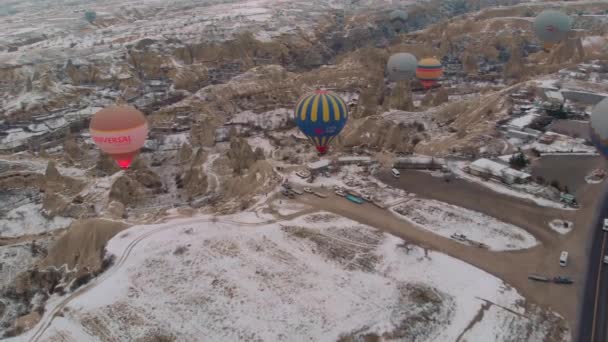Légi Felvétel Hőlégballonok Mozgásáról Tündérkéményeken Keresztül Hótakaró Cappadociában Törökország — Stock videók
