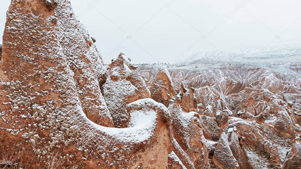 Fairy chimneys with snowy landscape at Devrent Valley in Cappadocia. Unique rock formations in Imaginary Valley in winter season in Cappadocia.