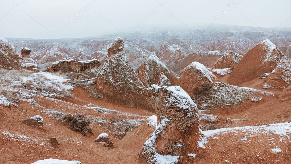 Fairy chimneys with snowy landscape at Devrent Valley in Cappadocia. Unique rock formations in Imaginary Valley in winter season in Cappadocia.