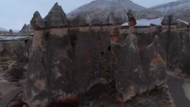 Türkiye 'nin başkenti Kapadokya' da karlı kış manzaralı Pasabag Vadisi 'ndeki büyük bacanın içindeki küçük mağara penceresinde tek başına duran kadının hava destansı manzarası
