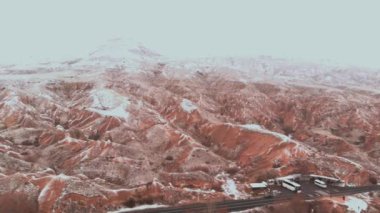 Kapadokya 'daki Devrent Valley' deki karlı manzaranın sinematik hava görüntüsü. Kapadokya 'da kış mevsiminde eşsiz Tuff Rock oluşumlarıyla dolu hayali vadide kar tarafından çevrelenmiş peri bacaları.. 