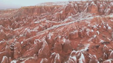 Kapadokya 'daki Devrent Valley' deki karlı manzaranın sinematik hava görüntüsü. Kapadokya 'da kış mevsiminde eşsiz Tuff Rock oluşumlarıyla dolu hayali vadide kar tarafından çevrelenmiş peri bacaları.. 