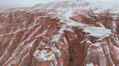 Kapadokya 'daki Devrent Valley' deki karlı manzaranın sinematik hava görüntüsü. Kapadokya 'da kış mevsiminde eşsiz Tuff Rock oluşumlarıyla dolu hayali vadide kar tarafından çevrelenmiş peri bacaları.. 