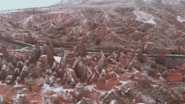 Kapadokya 'daki Devrent Valley' deki karlı manzaranın sinematik hava görüntüsü. Kapadokya 'da kış mevsiminde eşsiz Tuff Rock oluşumlarıyla dolu hayali vadide kar tarafından çevrelenmiş peri bacaları.. 