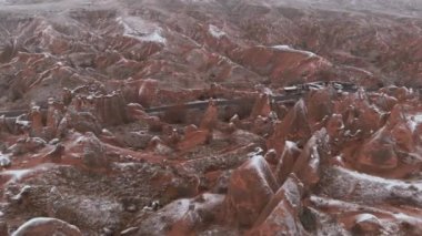 Kapadokya 'daki Devrent Valley' deki karlı manzaranın sinematik hava görüntüsü. Kapadokya 'da kış mevsiminde eşsiz Tuff Rock oluşumlarıyla dolu hayali vadide kar tarafından çevrelenmiş peri bacaları.. 