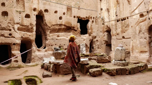 Woman alone at ancient Gumusler Monastery surrounded by old stones and ruins in Gumusler, Nigde