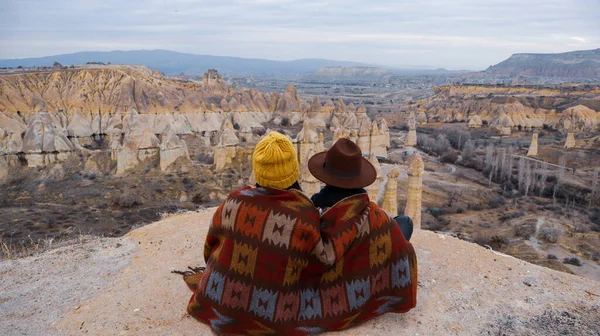 Travel couple watching mushroom shaped fairy chimneys at love valley in Cappadocia, Turkey. Happy couple watching the volcanic landscape at the valley of love in Goreme, Cappadocia