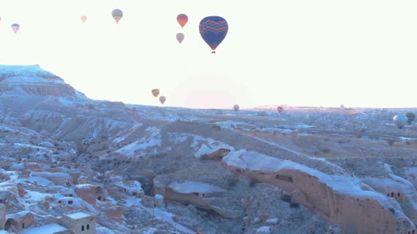 トルコのカッパドキアで冬の季節に谷を飛ぶ熱気球の空中映像 日の出にカッパドキアのカヴシン地方からの熱気球の空中ビュー — ストック動画