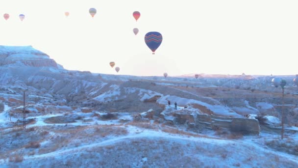 トルコのカッパドキアで冬の季節に谷を飛ぶ熱気球の空中映像 日の出にカッパドキアのカヴシン地方からの熱気球の空中ビュー — ストック動画