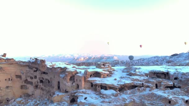 Luchtfoto Van Heteluchtballonnen Die Oude Grotwoningen Vliegen Met Besneeuwd Vulkanisch — Stockvideo