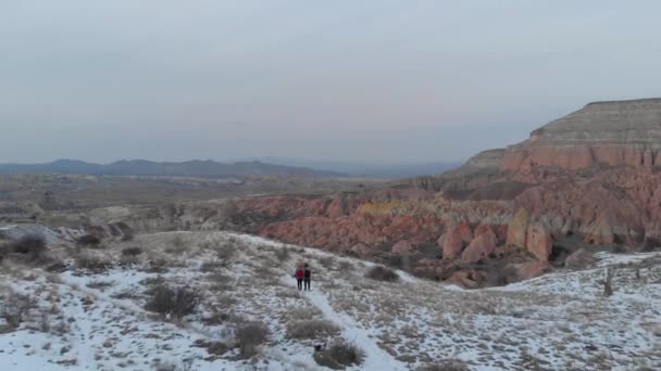 在土耳其的卡帕多西亚 一对可爱的旅行夫妇在雪地上漫步的美丽的空中风景覆盖了红谷 形成了壮观的火山岩 — 图库视频影像