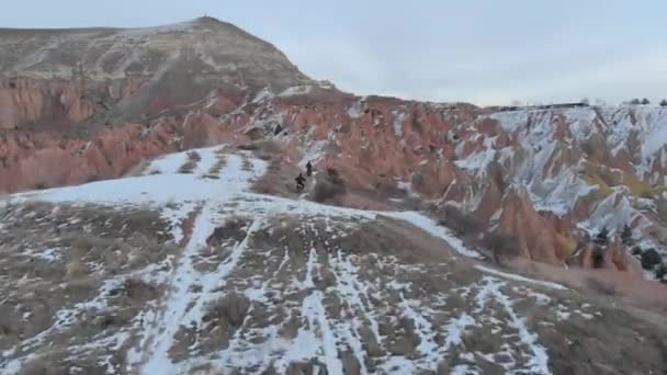 土耳其卡帕多西亚红谷雪地上骑摩托车环绕火山景观的空中跟踪 — 图库视频影像