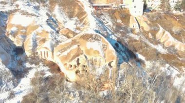 Türkiye 'nin Kapadokya kentinde güneş doğarken karla kaplı Güvercin Vadisi ve mağara evleri hava manzarası