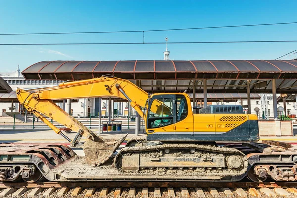 Bagger steht auf dem Bahntransporter neben dem Bahnsteig. — Stockfoto