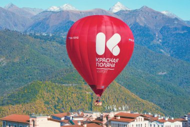 Krasnaya Polyana, Rusya - 13 Ekim 2019: Kasabanın üzerinde dağ manzarası arka planında kırmızı sıcak hava balonu.