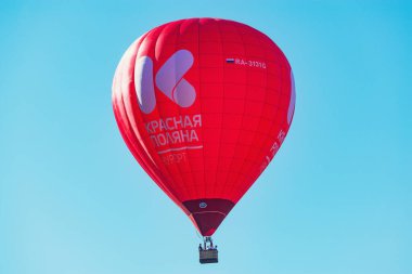 Krasnaya Polyana, Rusya - 13 Ekim 2019: Kırmızı sıcak hava balonu mavi arka planda kasabanın üzerinde.