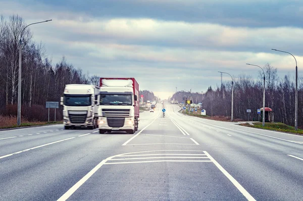 Los camiones de carga se mueven rápido en la carretera al atardecer . — Foto de Stock