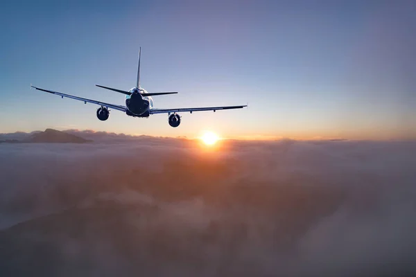 Flying of the passenger plane above the clouds and mountains. — Stock Photo, Image