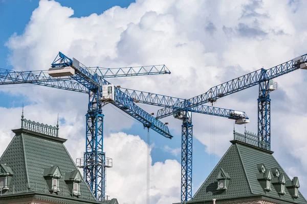 Construction cranes above the roof. — Stock Photo, Image