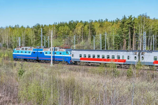 Tren de pasajeros se mueve en el fondo del bosque en el día de primavera . — Foto de Stock