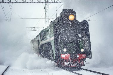 Retro buhar treni kış karlı bir zamanda tren istasyonundan ayrılır..