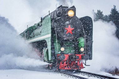 Retro buhar treni kış karlı bir zamanda tren istasyonundan ayrılır..