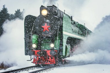 Retro buhar treni kış karlı bir zamanda tren istasyonundan ayrılır..