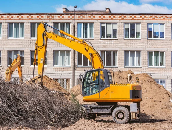 Excavator digs a hole on the construction site territory.