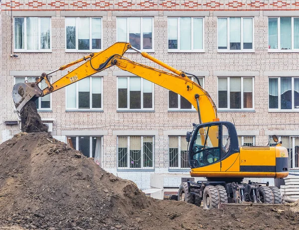 Excavator digs a hole on the construction site territory.