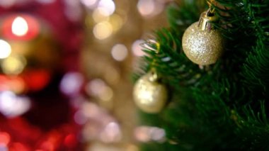 Altın top, Noel ağacındaki oyuncak rüzgardan sallanıyor. Parlak arkaplan bulanıklığı. Yeni yıl için sihirli video ve noel yayını, sunumlar, müzik videosu.