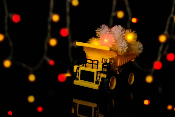 Weihnachtskarte. Das Kinderauto trägt bunte festliche Girlanden. dunkler Hintergrund, gelbe Farbe. Frohe Weihnachten — Stockfoto