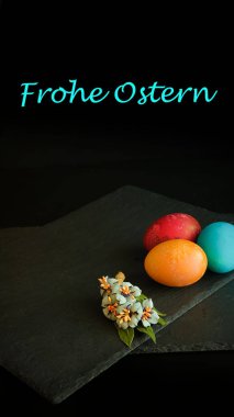 Birkaç tane renkli Paskalya yumurtası. Yakınlarda çiçek açan bir dal var.