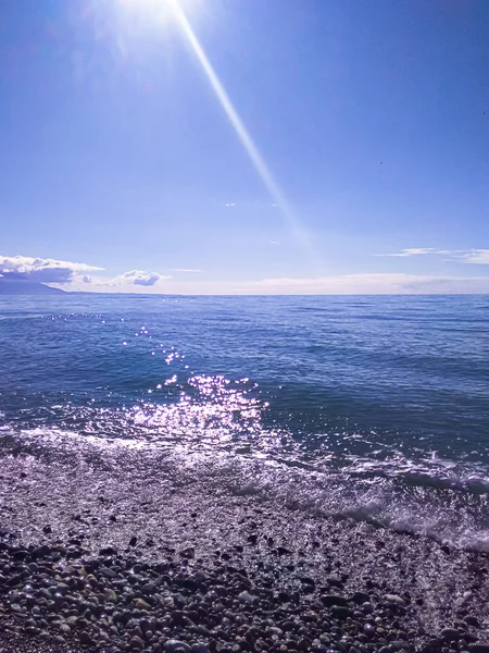 Noon on the seashore, sea stones, a ray of sun falls from above