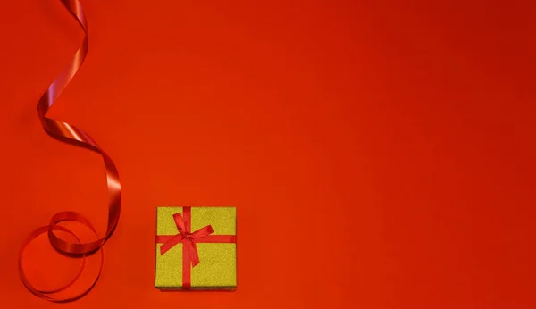 Klein cadeautje met rode strik op rode achtergrond. Vrije ruimte voor uw tekst. Valentijnsdag, Kerstmis, vakantie — Stockfoto