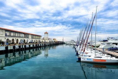 Beyaz lüks yatlar ve beyaz tekneler bir marinaya demirlemiş. Göz kamaştırıcı, muhteşem liman, deniz ve gökyüzü manzarası. Sakin ol. Rusya, Soçi, 12.26.2019