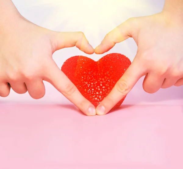 Hand heart and red heart shape.Pink background.Sun rays.Sunshine.Copy space for text.