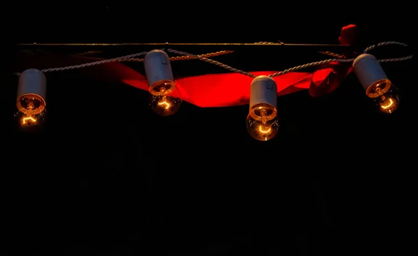Eine Girlande aus Glühbirnen auf schwarzem Hintergrund. — Stockfoto
