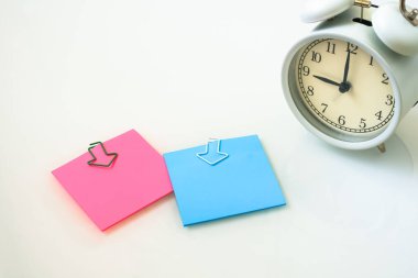 Beyaz alarm saati ve beyaz arka planda renkli yapışkan notlar. Çalışma zamanı kavramı. İşyeri