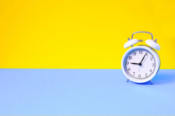 Vintage alarm clock on two tone solid color yellow and light blue background — Stockfoto