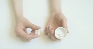 Bir kadının avucundaki beyaz tablet. El beyaz arka planda kapsül.