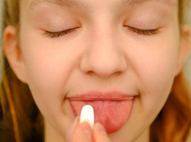 Sarışın bir kızın yüzü, dilinin üstüne hap koyar, baş ağrısı, mide ağrısı, vitamin, sakinleştirici, sağlık konsepti gibi ilaçlardan ilaç alır.