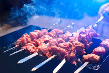 Terbiye edilmiş şiş kebap, metal şişte kuzu eti, mavi duman, indirim. Kapatın. Odaklanmamış