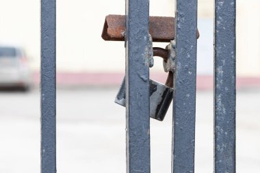 Kapalı ve kilitli kapı ızgarası gümüş asma kilitle. Menteşelerin üzerindeki metal bir kilit ızgaranın üzerinde asılı duruyor. Güvenlik kavramı veya yasağı, tasarımınız için kopyalama alanı