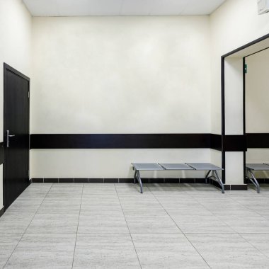 Modern bir ofis binasında boş bir koridor. Açık renkli duvarları ve kahverengi kapıları olan bir salon..